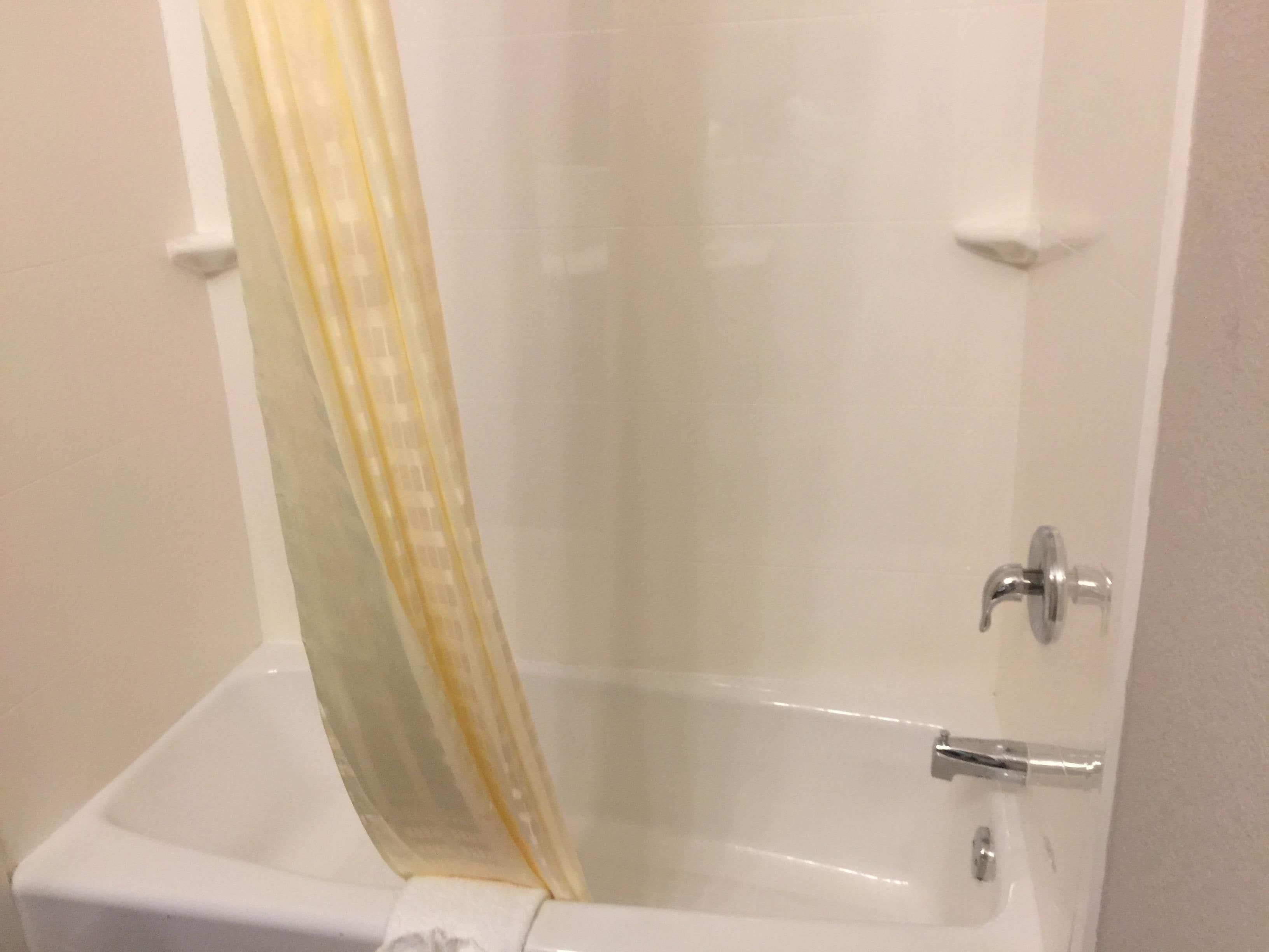 A bathroom with a bathtub, a shower curtain, and a faucet.