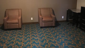 Una habitación con dos sillones, un escritorio y una alfombra estampada.