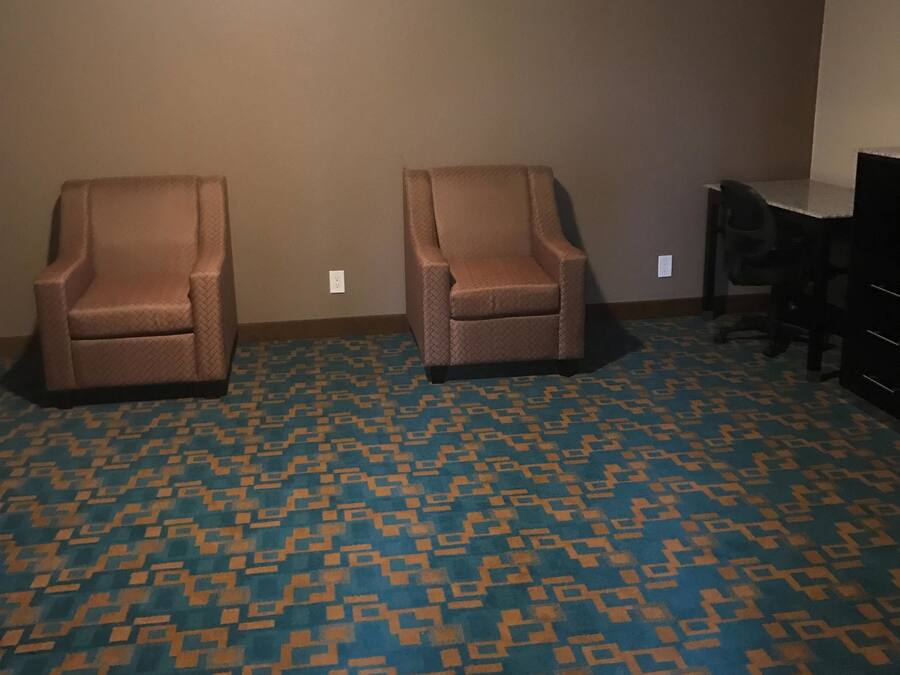 Una habitación con dos sillones, un escritorio y una alfombra estampada.