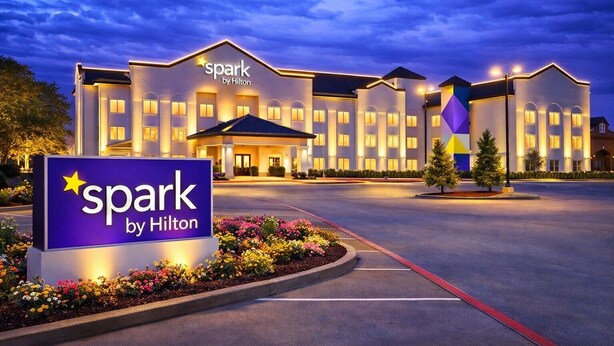 Un hotel con un letrero que dice 'spark by Hilton' y una entrada bien iluminada.