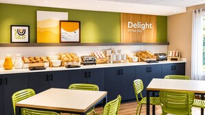 Un área de desayuno moderna con mostrador que exhibe pasteles, un tostador y una estación de café.