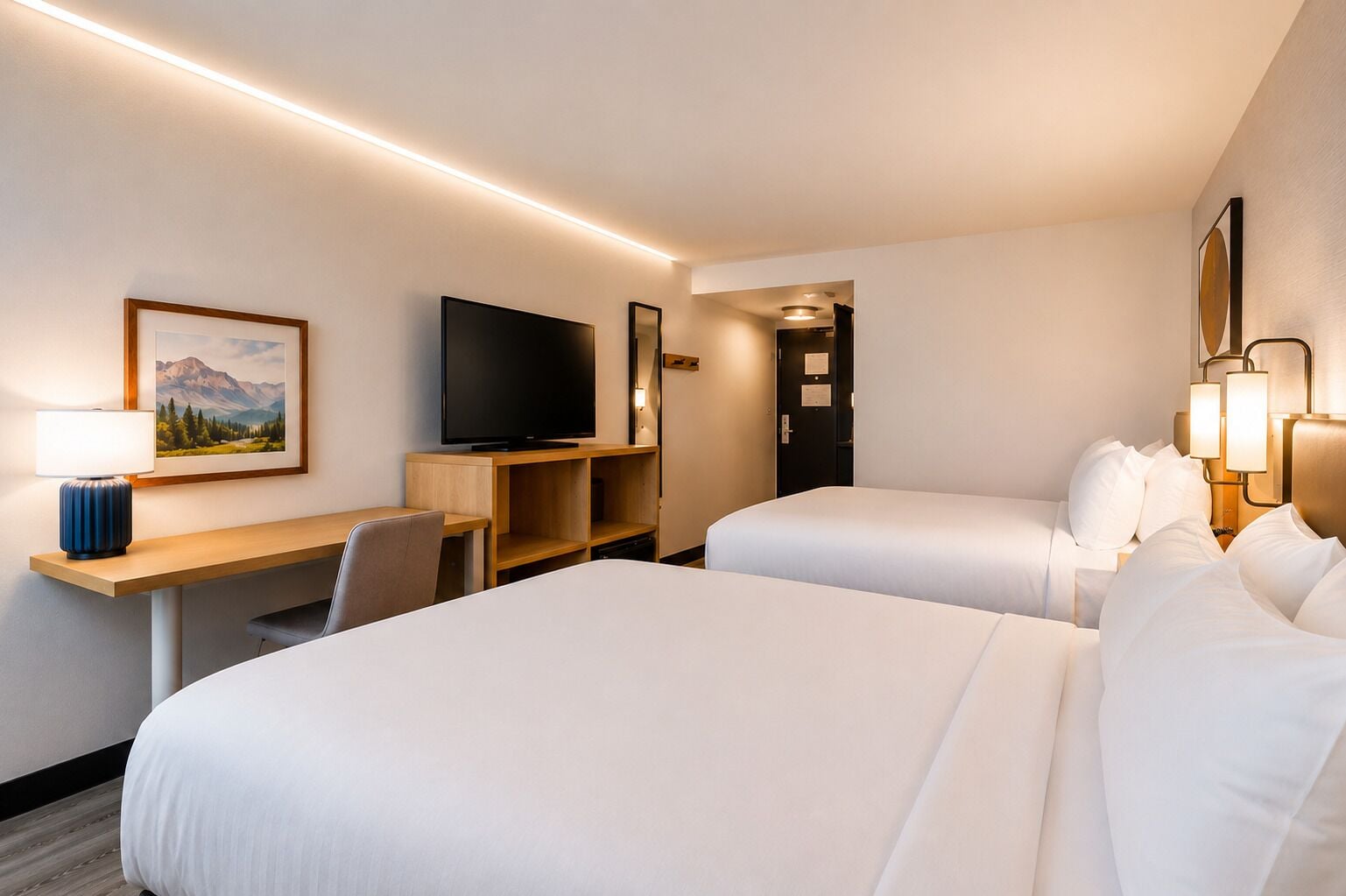 A hotel room with two beds, a desk with a TV, a lamp, and a framed picture on the wall.