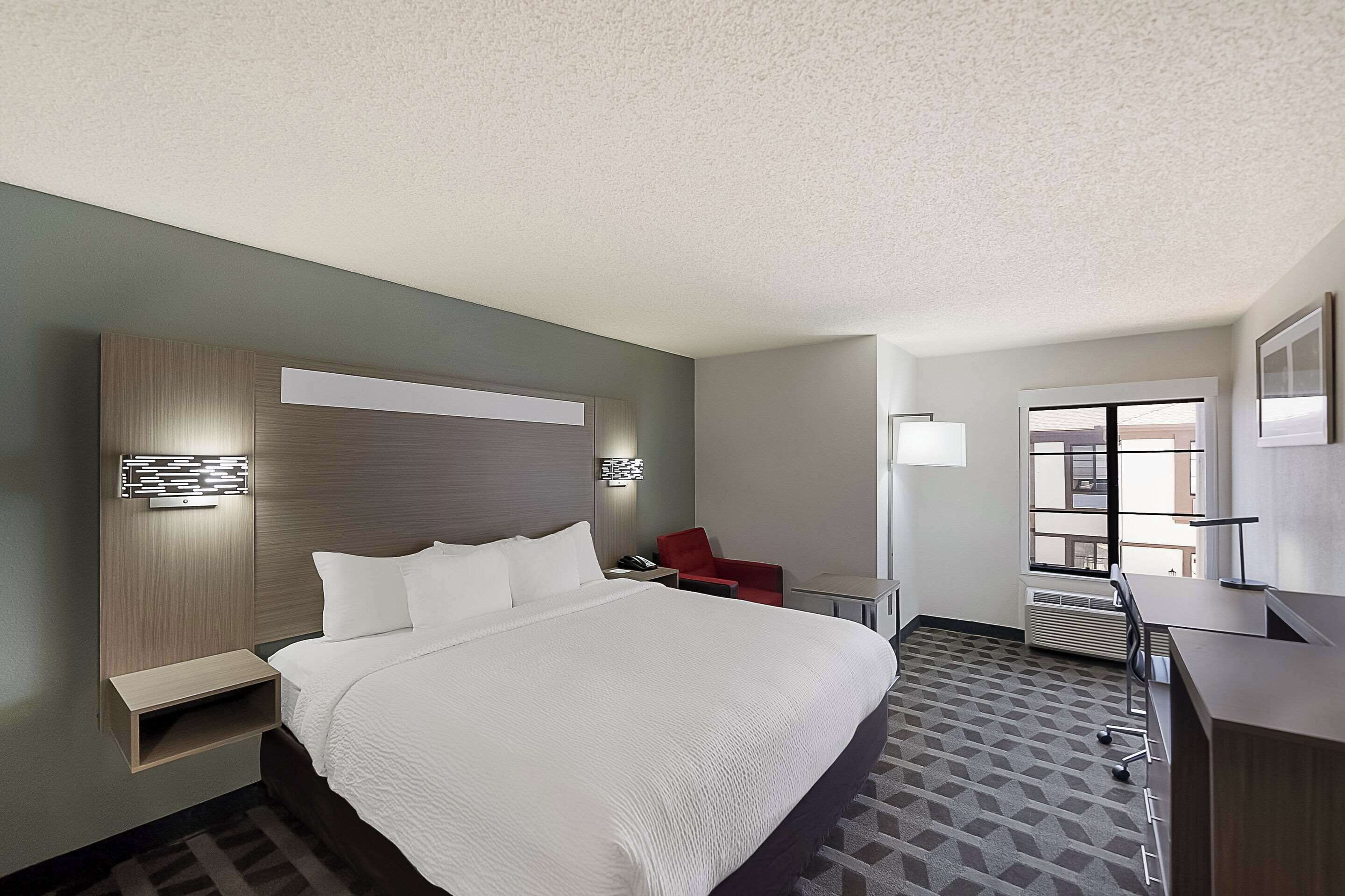 Een hotelkamer met een groot bed, een bureau, een stoel en een raam.