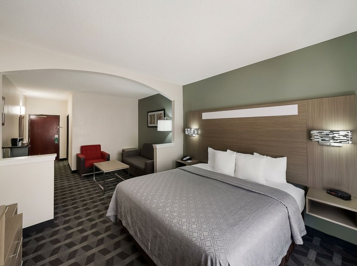 Ein Hotelzimmer mit einem großen Bett, einem Schreibtisch, einem roten Sessel und einem kleinen Tisch.