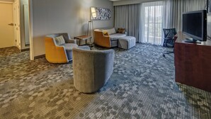 A hotel room with a grey carpet, a sofa set, a TV, and a large window with curtains. - Courtyard by Marriott Abilene Southwest/Abilene Mall South (Abilene)