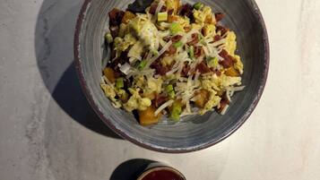 A bowl of food with a small container of sauce.