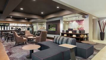 A modern lounge area with sofas, chairs, a bar, and a television.