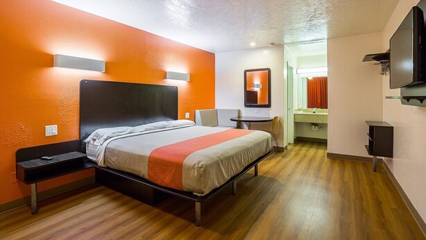 Una habitación de hotel con cama, mesita de noche, silla y televisión.