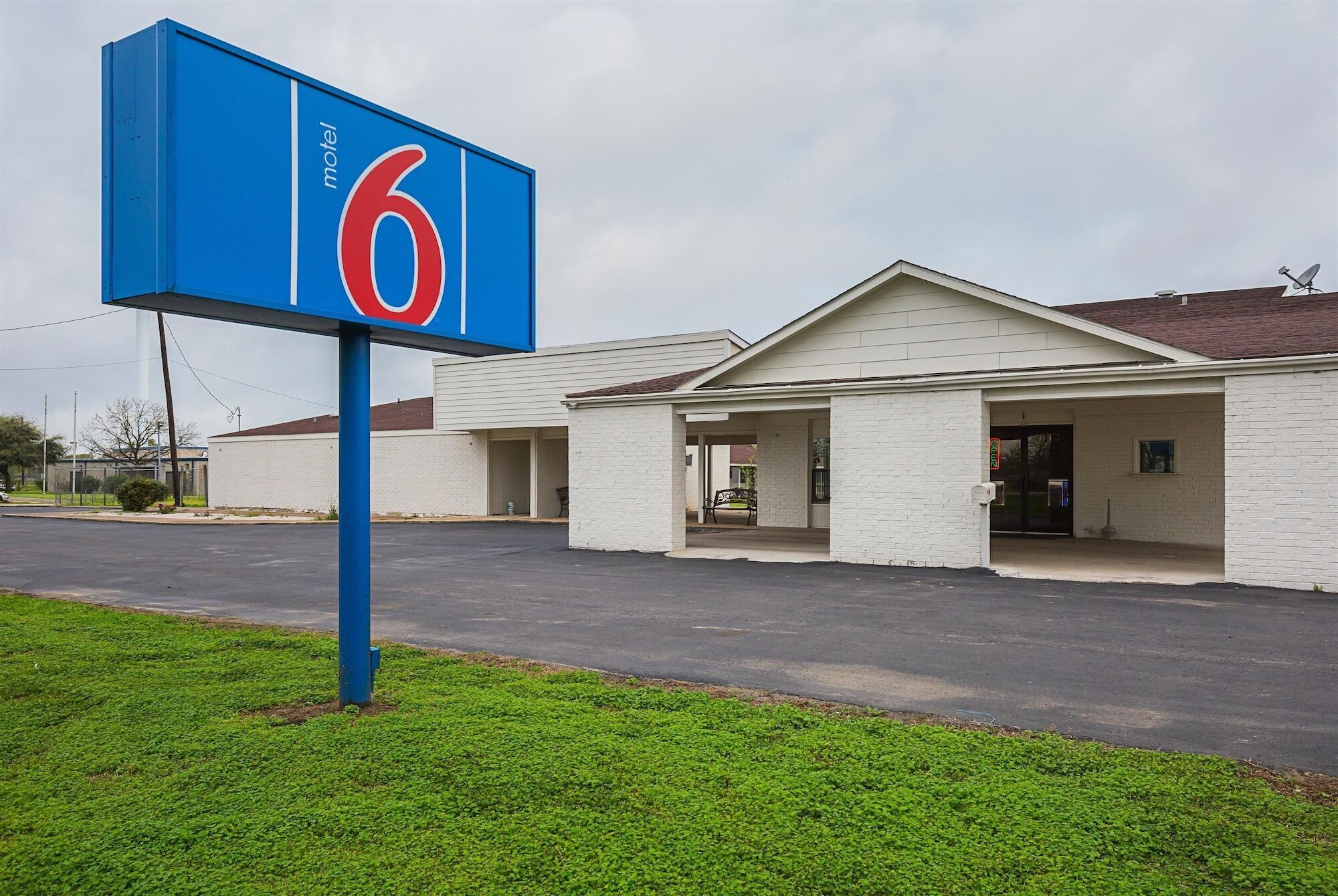 A motel with a prominent '6' sign, a parking lot, and a building with a simple, functional design.