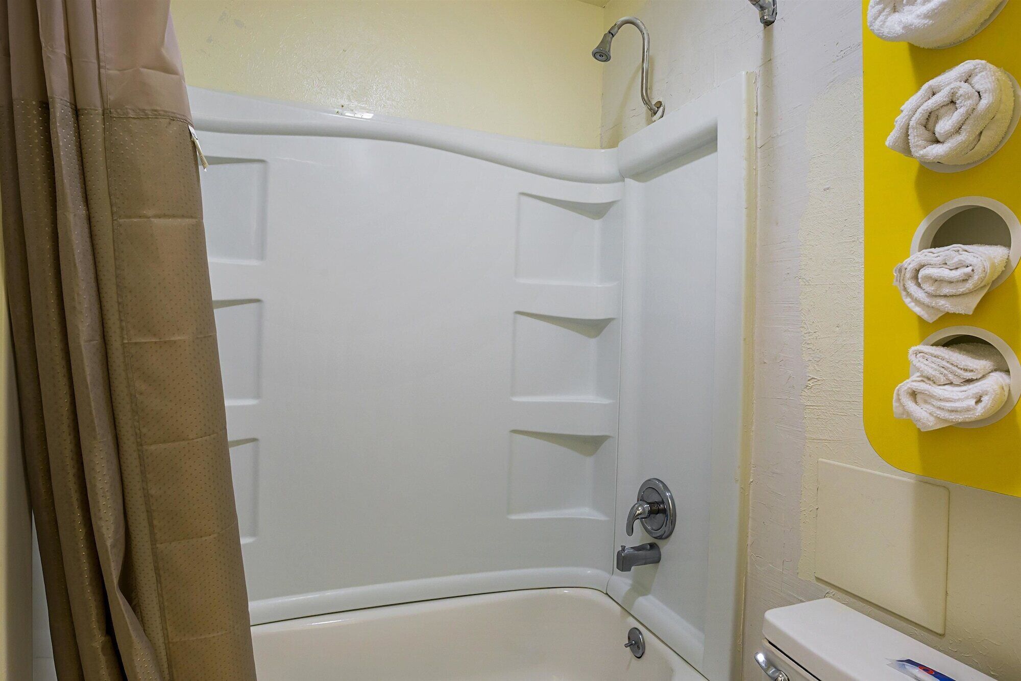 A bathroom with a bathtub, a toilet, and a towel rack with towels.