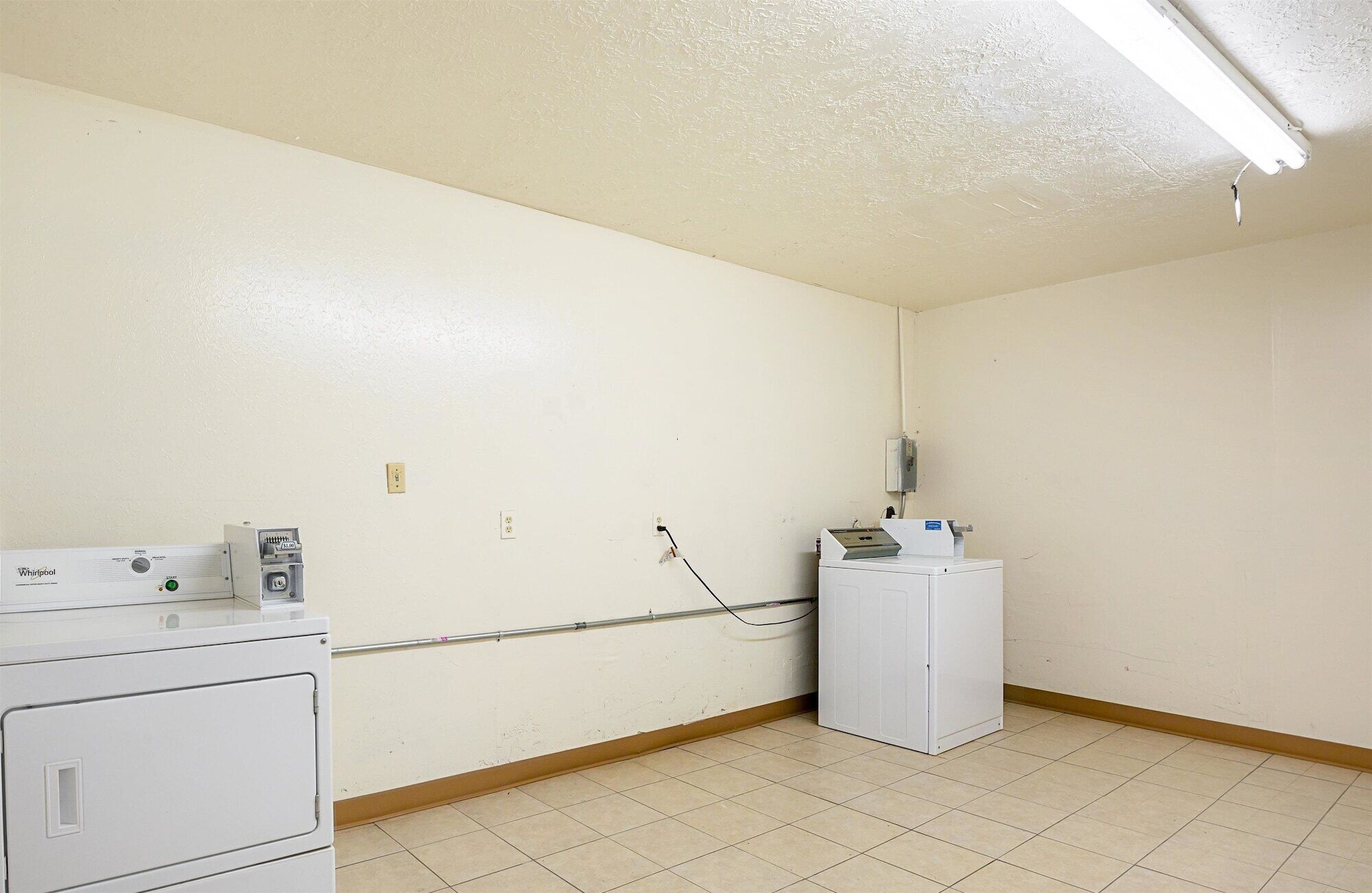 A laundry room with a Whirlpool washer and dryer, a utility meter, and a water heater on the wall.