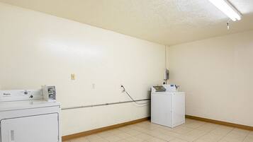 A laundry room with a Whirlpool washer and dryer, a utility meter, and a water heater on the wall.
