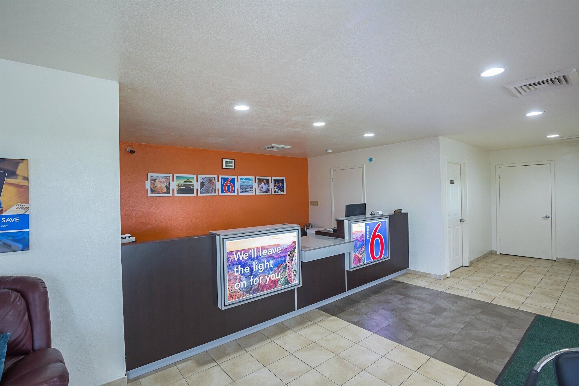 A hotel reception area with a counter, a clock, and a digital display.