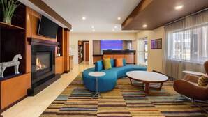 A modern living room with a fireplace, a blue sectional sofa, and a flat-screen TV mounted on the wall.