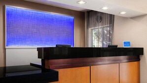 A reception desk with a wooden finish, a black countertop, and a blue illuminated wall feature.