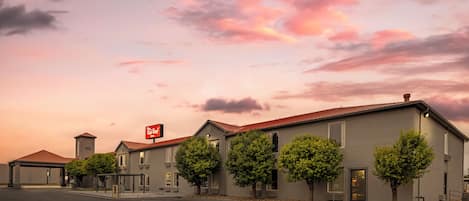 A Red Roof Inn with a modern architectural style, featuring a flat roof, a series of windows, and a parking lot in front.