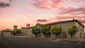 A Red Roof Inn with a modern architectural style, featuring a flat roof, a series of windows, and a parking lot in front. - Red Roof Inn Dumas (Dumas)