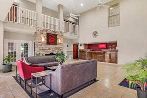 A spacious lobby with a stone fireplace, a reception desk, and a high ceiling with a fan. - Red Roof Inn Dumas (Dumas)