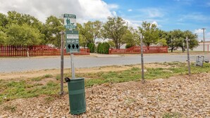 A dog waste station with a sign instructing to clean up after your dog. - Red Roof Inn Dumas (Dumas)