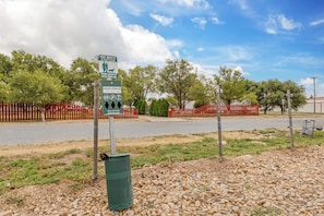 A dog waste station with a sign instructing to clean up after your dog. - Red Roof Inn Dumas (Dumas)