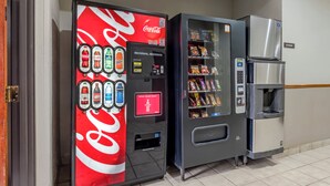 A vending machine with a Coca-Cola logo and a snack vending machine next to a refrigerator. - Red Roof Inn Dumas (Dumas)