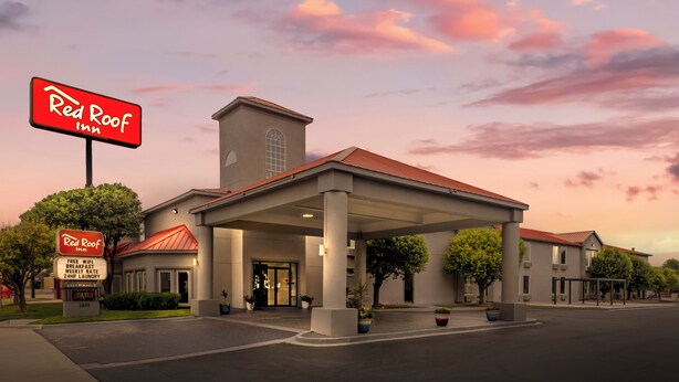 A Red Roof Inn with a covered entrance, a standalone sign, and a clear sky. - Red Roof Inn Dumas (Dumas)