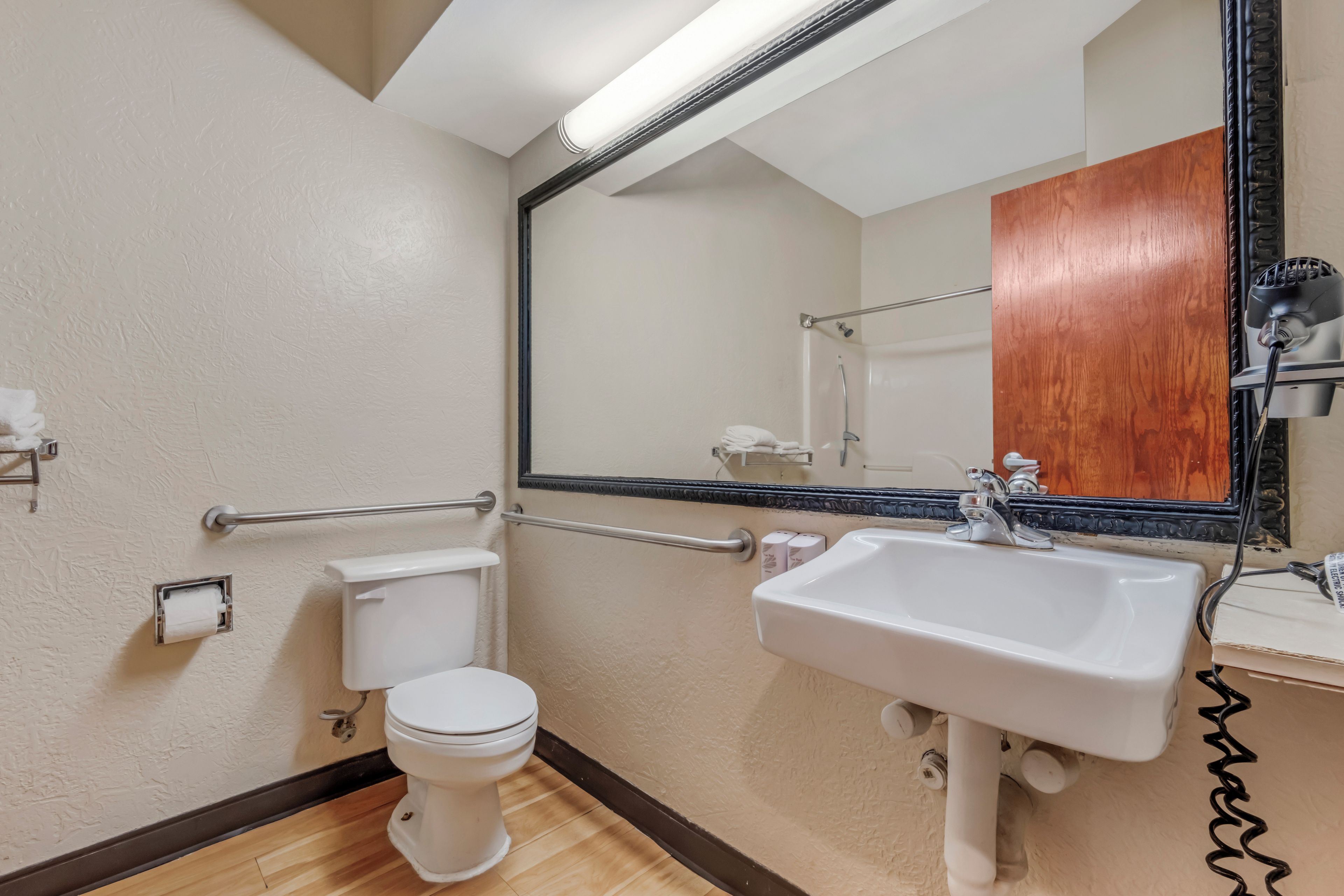 A bathroom with a toilet, sink, and mirror.