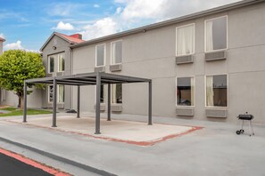 A building with a covered outdoor seating area, multiple windows, and a tree in the background. - Red Roof Inn Dumas (Dumas)