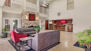 A spacious lobby with a stone fireplace, a reception desk, and a high ceiling with a fan. - Red Roof Inn Dumas (Dumas)