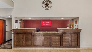 A reception desk with a clock above it, a sign indicating free Wi-Fi, and a red wall. - Red Roof Inn Dumas (Dumas)