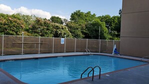 A swimming pool with a safety fence, a ladder, and a blue chair.