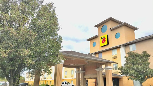 A hotel entrance with a covered area, columns, and a sign indicating room availability.