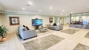 A hotel lobby with two sofas, a coffee table, a TV, and a reception desk. - Super 8 by Wyndham Temple I-35 (Temple)