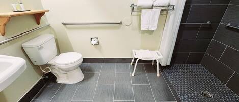 Um banheiro com vaso sanitário, um banquinho pequeno, porta-toalhas e cortina de chuveiro.