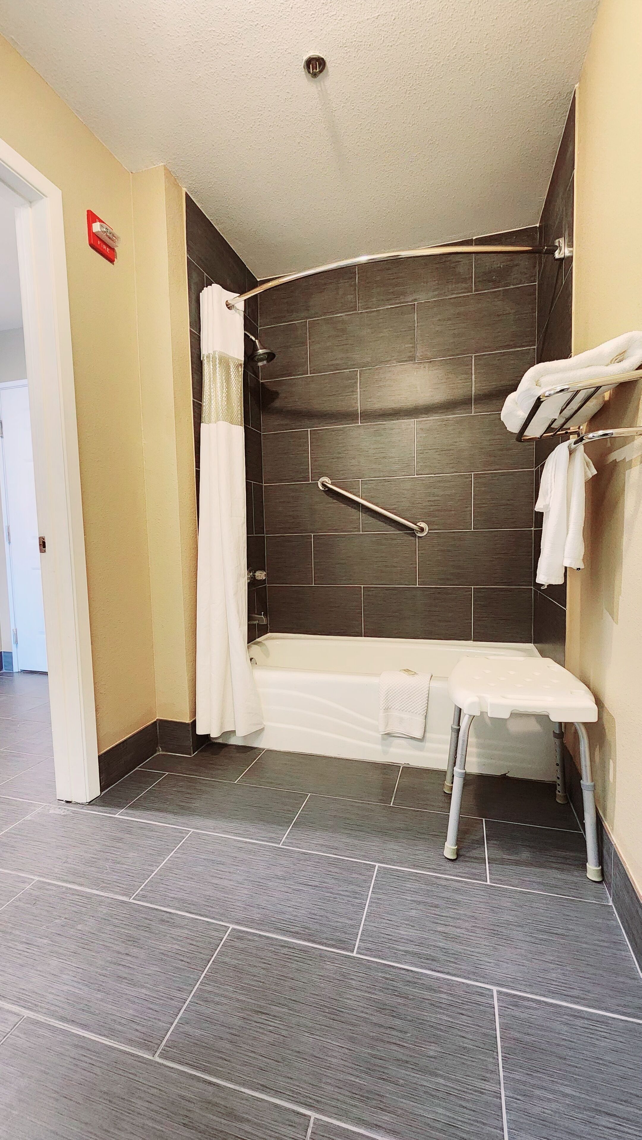 Un baño con ducha, un banco y un perchero.
