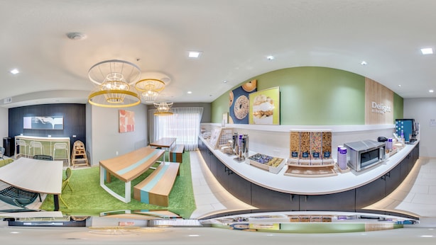 Ein modernes Interieur mit einer gebogenen Rezeption, einer Sitzecke mit Bänken und einem Kinderspielbereich.