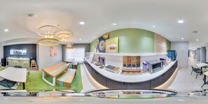 A modern interior with a curved reception desk, seating area with benches, and a children's play area. - Spark by Hilton Terrell (Terrell)