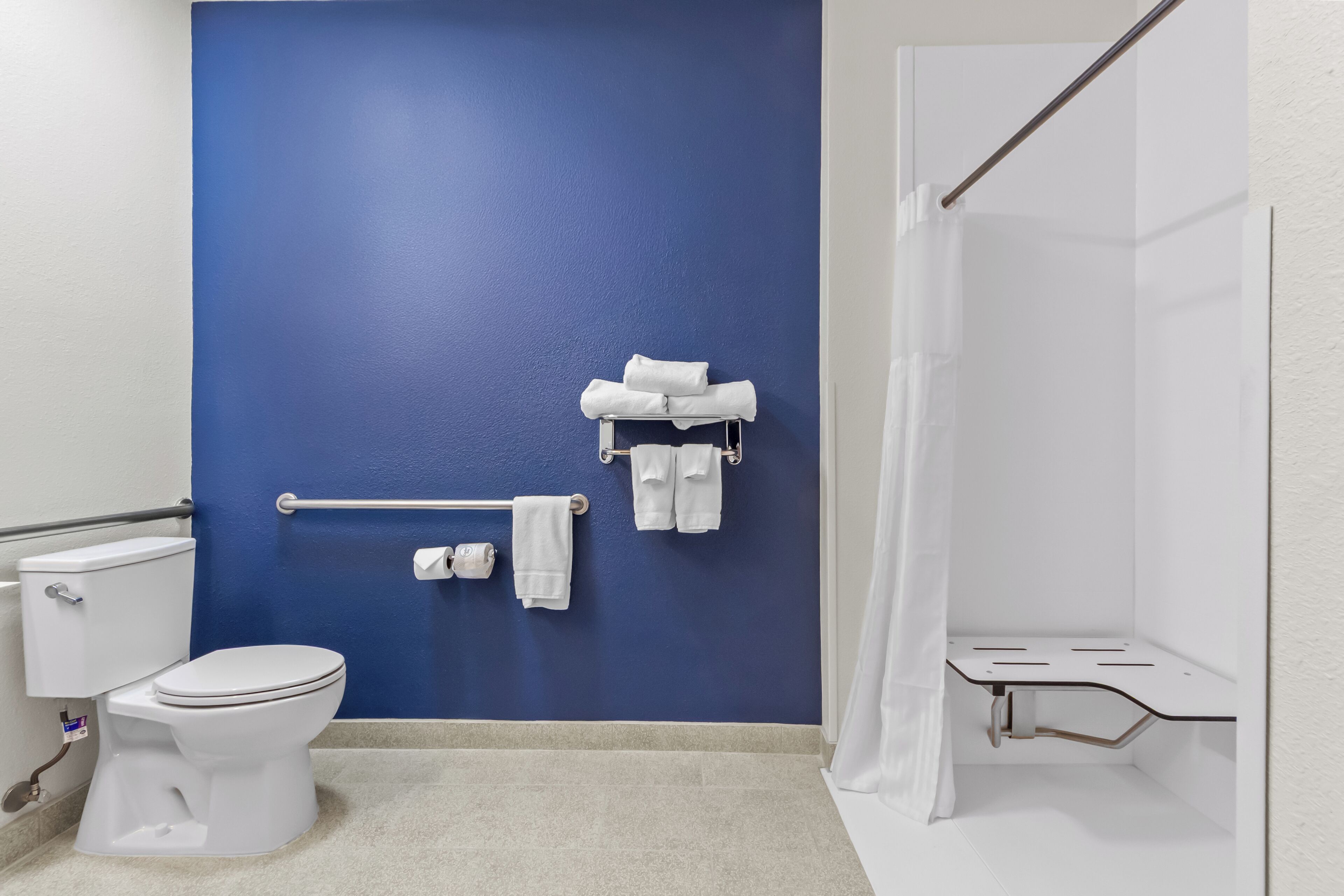 Un baño con pared azul, inodoro blanco y zona de ducha.