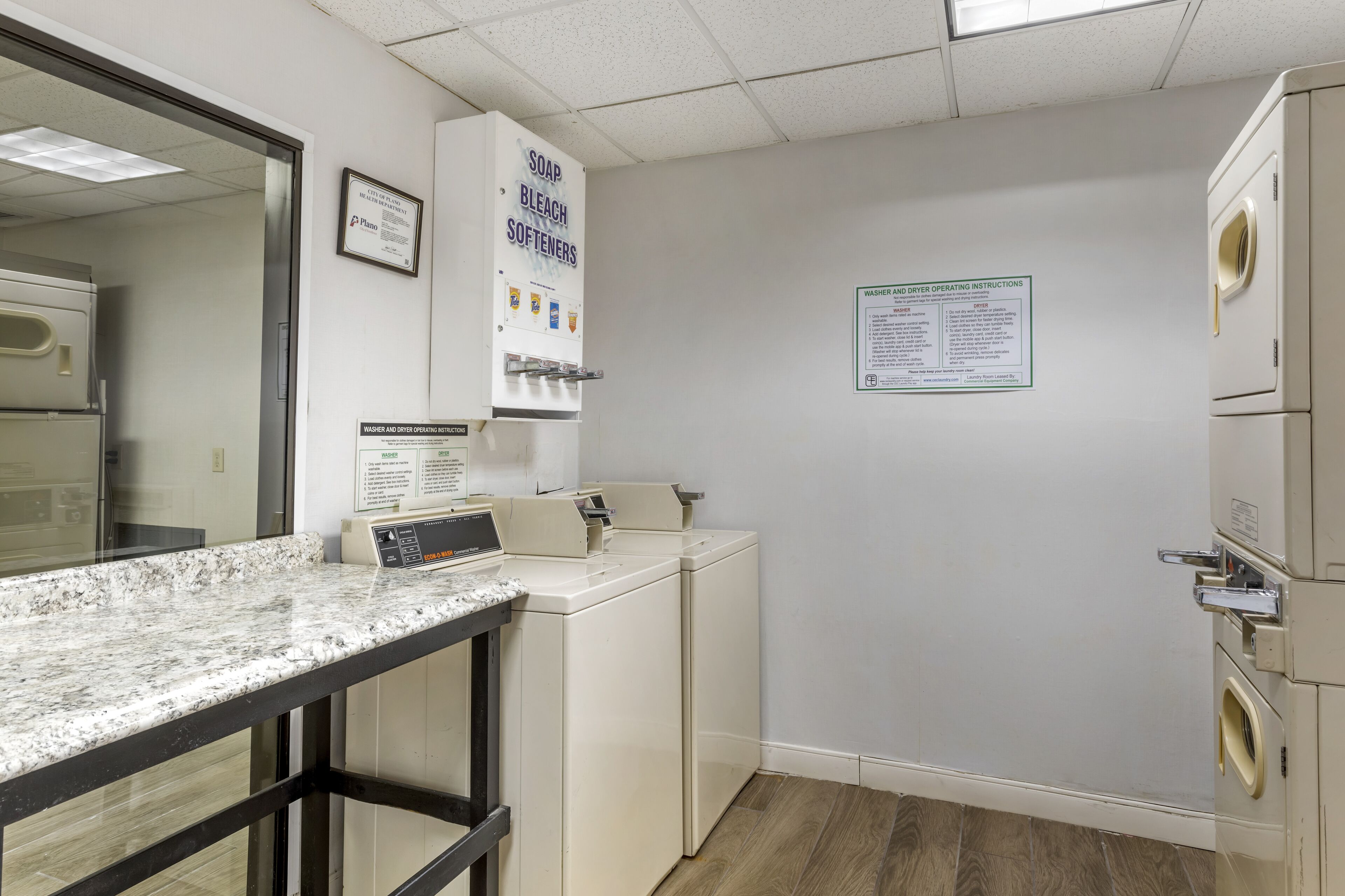 A laundry facility with a countertop, washing machines, and operating instructions on the wall.