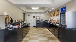 A modern kitchen with checkered flooring, stainless steel appliances, and a variety of food items displayed on the counter. - Comfort Inn Plano-Dallas (Plano)