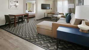A hotel room with a bed, a desk, a chair, a sofa, a TV, and a lamp. - Residence Inn by Marriott Dallas Addison/Quorum Drive (Dallas)
