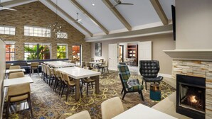A spacious dining area with high ceilings, exposed beams, and a fireplace. Tables and chairs are arranged for dining. - Residence Inn by Marriott Dallas Addison/Quorum Drive (Dallas)