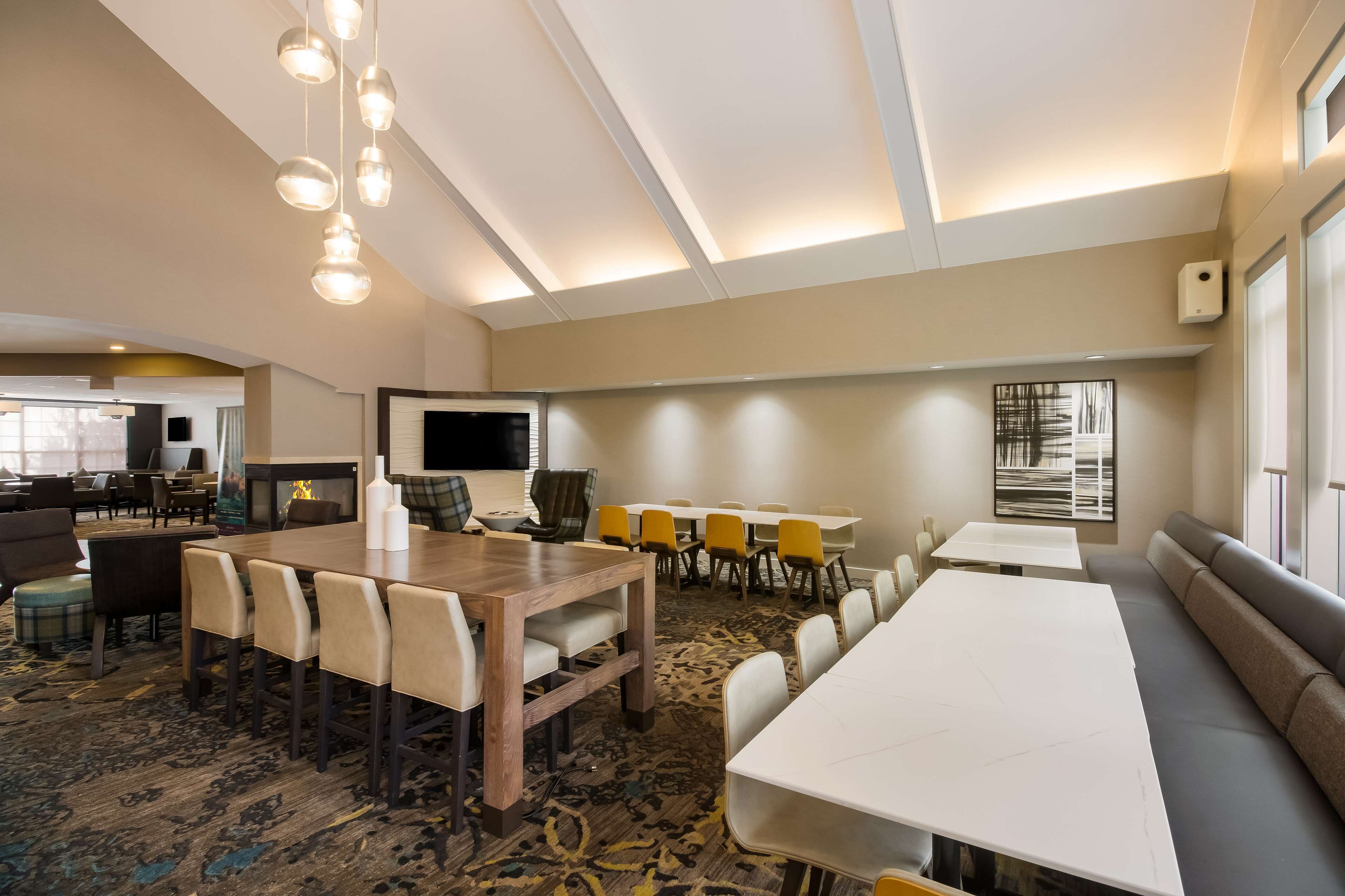A conference room with a large table, chairs, a sofa, and a TV screen.