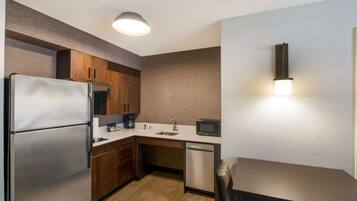 A compact kitchen with a refrigerator, microwave, sink, and dishwasher.