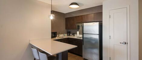 A modern kitchen with a white island, dark wooden cabinets, stainless steel appliances, and a white door.