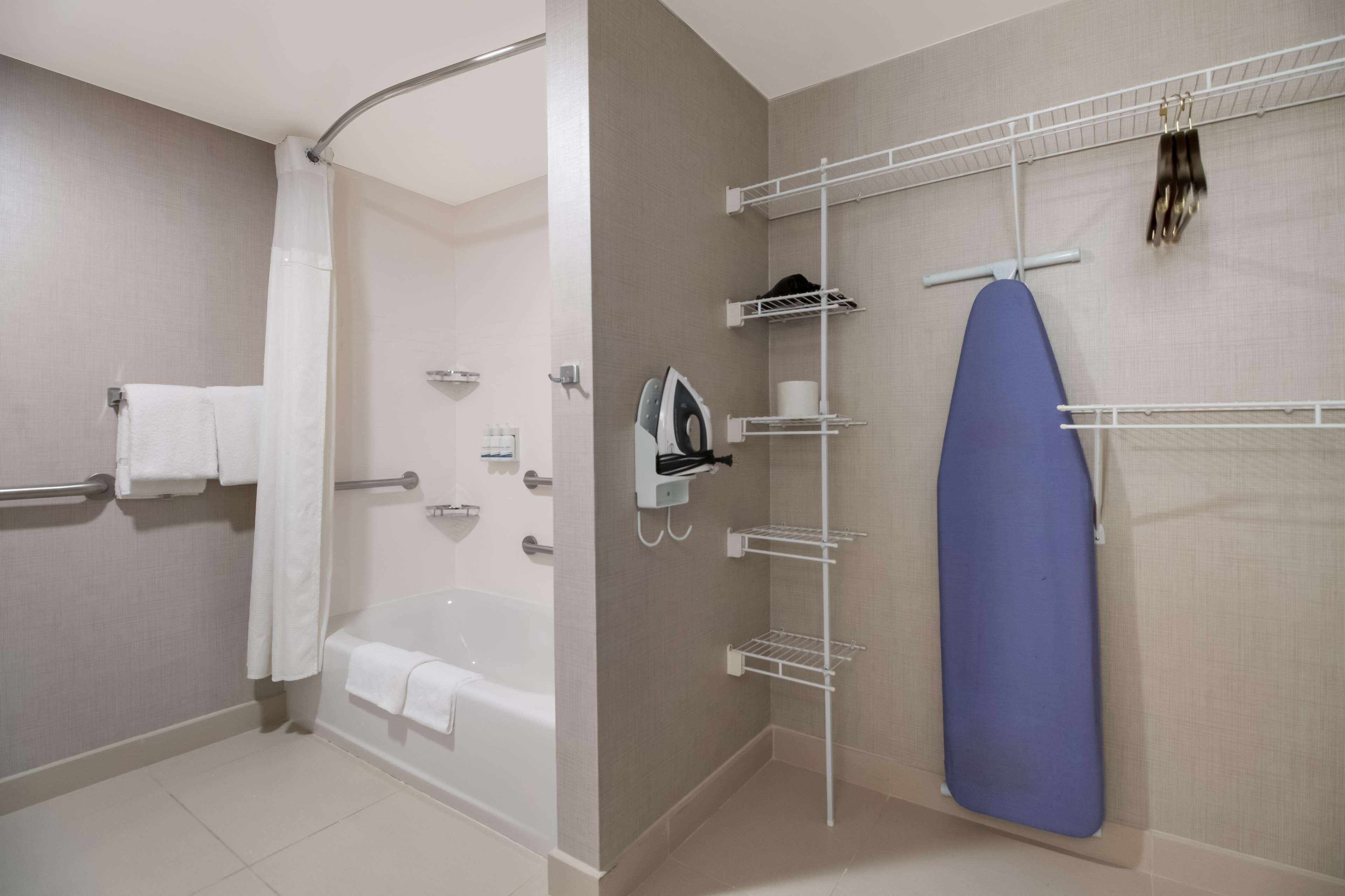 A bathroom with a bathtub, a shower, and a wall-mounted ironing board.