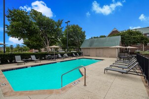 Una piscina al aire libre, sombrillas, sillones reclinables de piscina