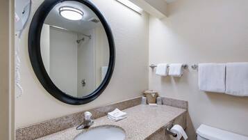 A bathroom with a round mirror, a sink, a toilet, and a towel rack.