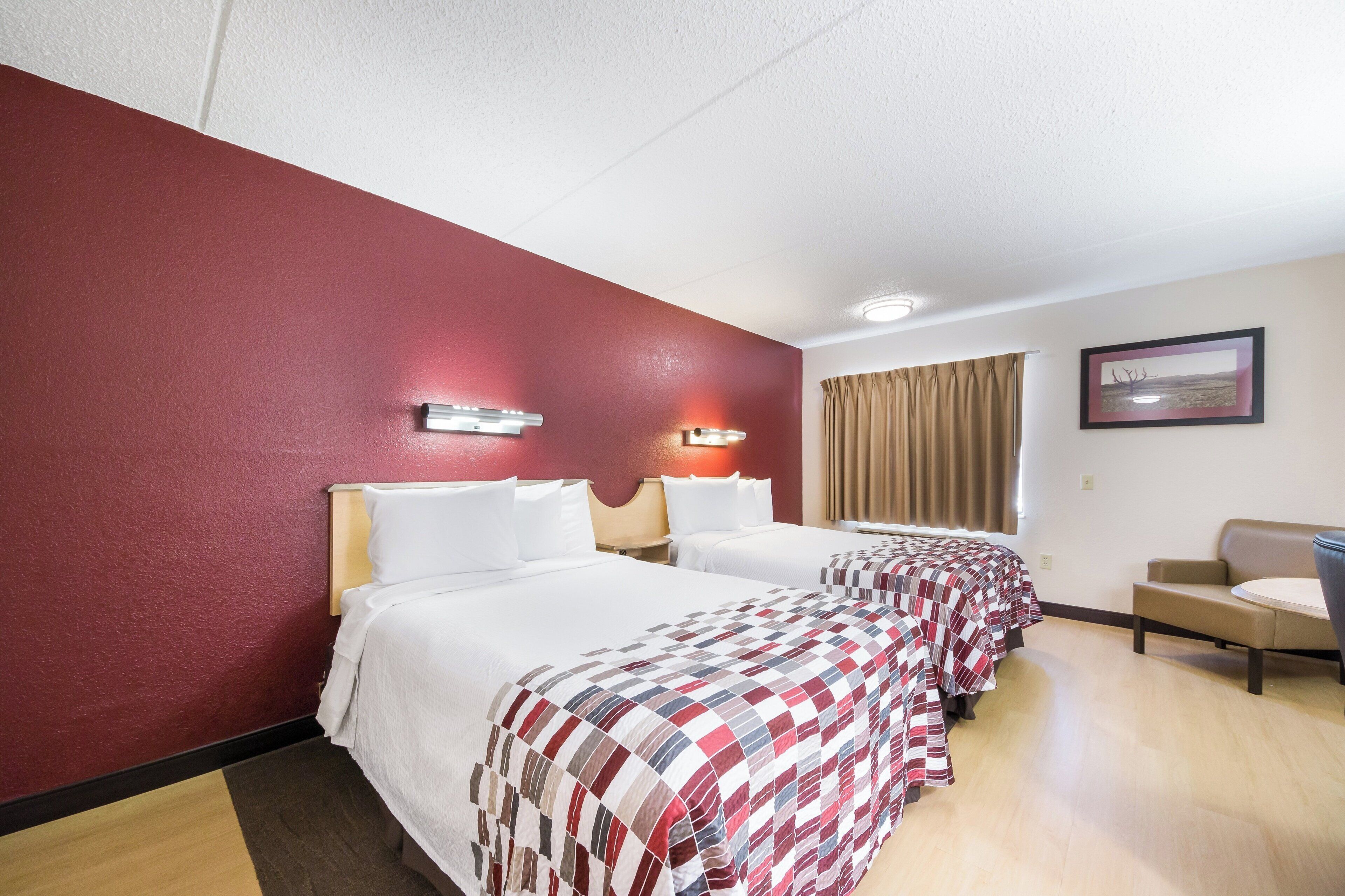 A hotel room with two beds, a desk, and a chair.