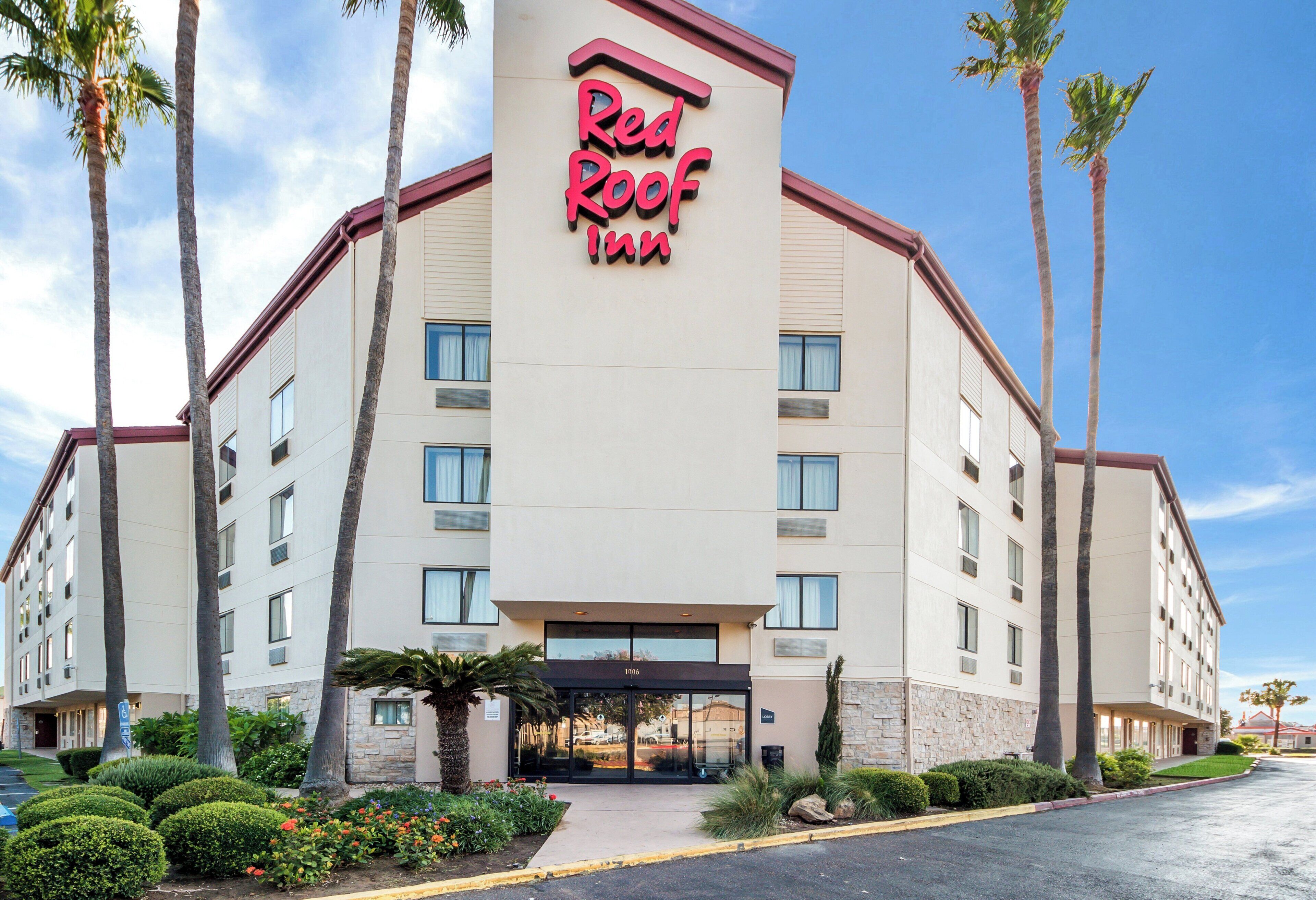 Un hotel Red Roof Inn con fachada plana, múltiples ventanas y una entrada central.